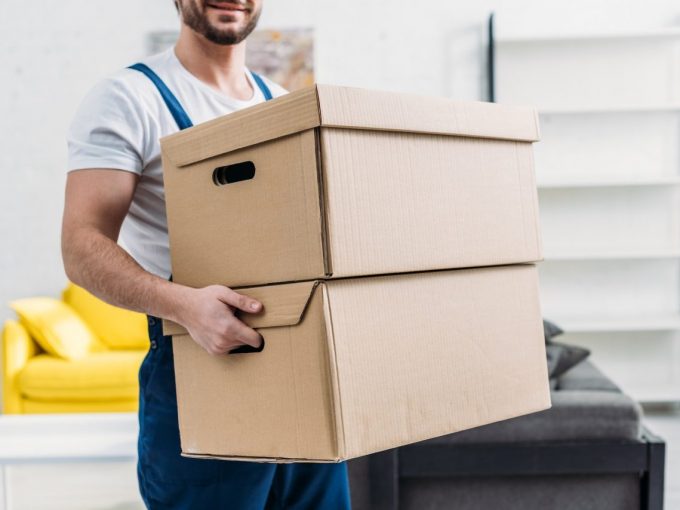 cropped-view-of-mover-in-uniform-carrying-cardboard-boxes-in-apartment.jpg